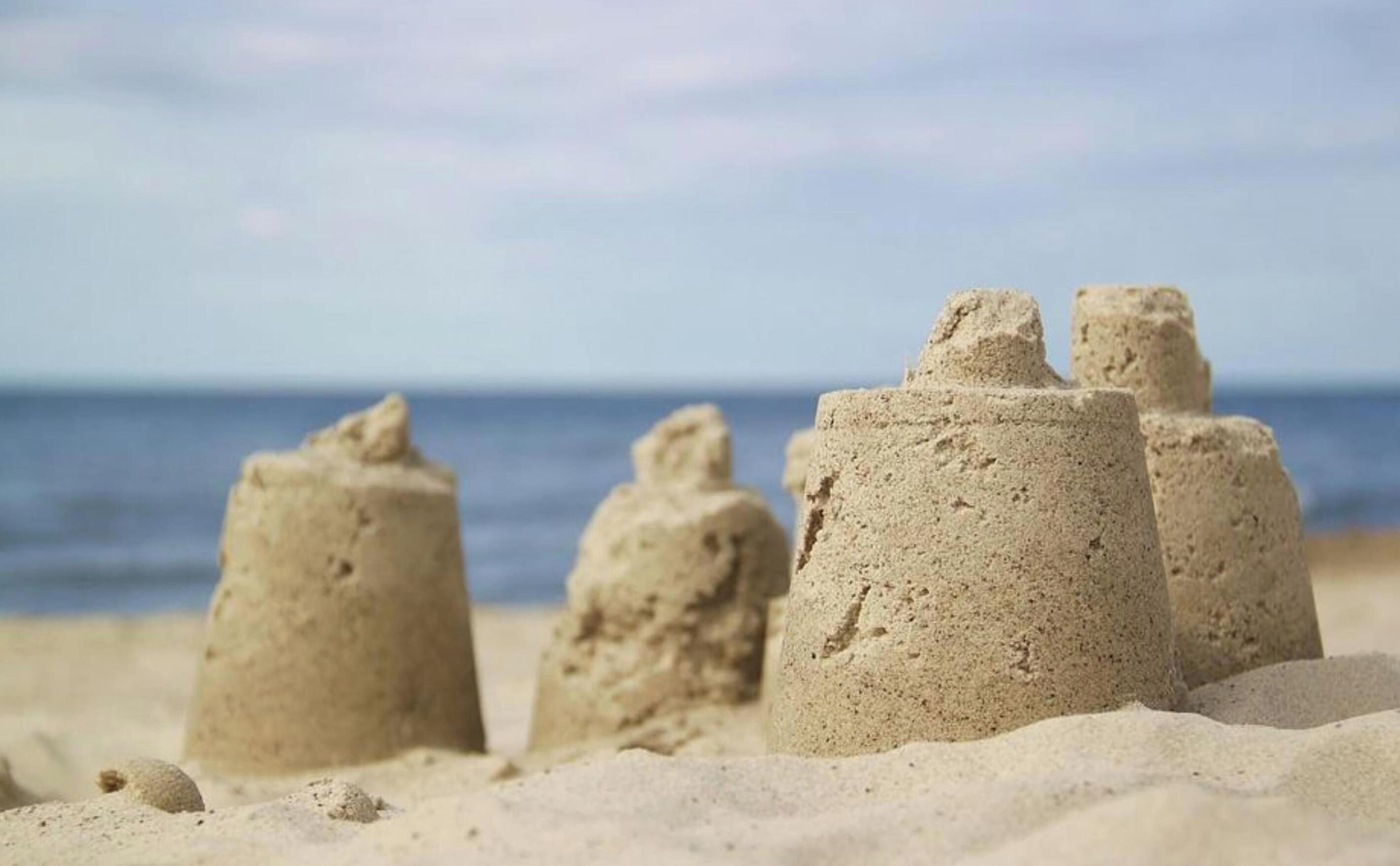 Estructuras de arena en una playa, con el océano al fondo.
