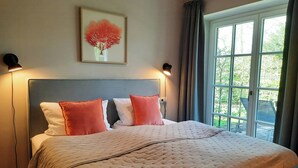 A bedroom with a bed, two bedside lamps, a window with curtains, and a framed artwork on the wall. - East Frisian chic: holiday home in country house with private lake (Friedeburg)