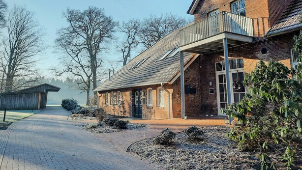 A brick building with a balcony, a covered walkway, and a clear sky. - East Frisian chic: holiday home in country house with private lake (Friedeburg)