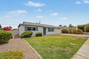 Ein Bungalow mit Vordergarten, Kiesweg und kleinem Garten.