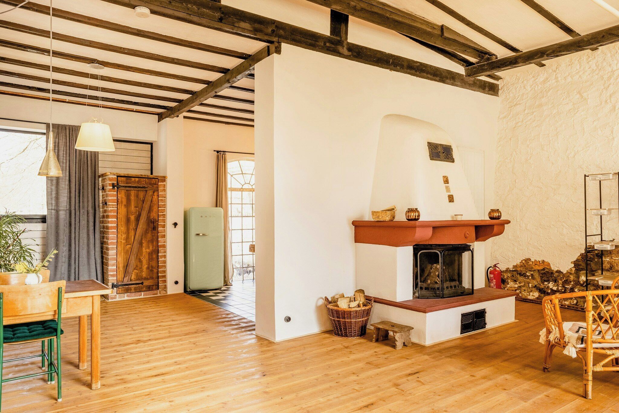 A rustic interior with a fireplace, wooden flooring, and a brick wall.