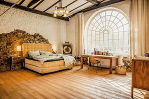 A bedroom with a stone wall, a bed, a desk, and a large arched window. - Immerse yourself into the magic of this studio and discover your creative side (Kall)