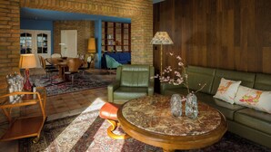 A living room with a brick wall, a green leather sofa, a round coffee table, and a bookshelf. - Stylish apartment Zander on the Eider river bend (Stapel)