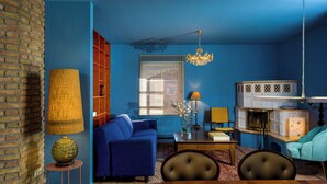 A living room with a blue sofa, a dining table, and a kitchen area with white cabinets. - Stylish apartment Zander on the Eider river bend (Stapel)