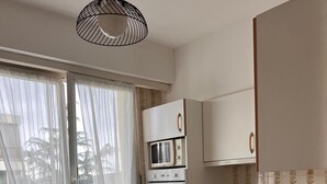 Eine kleine Küche mit Waschmaschine, Mikrowelle, Backofen und Spüle.