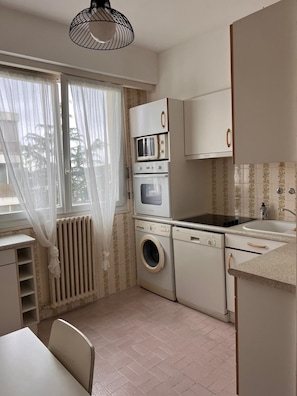 A compact kitchen with a washing machine, microwave, oven, and a sink. - Apartment near beaches, balcony, parking (Antibes)