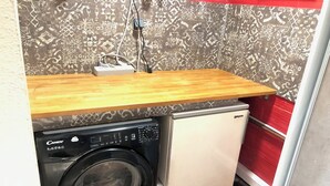 A compact laundry area with a Candy brand washer and a small refrigerator. - Room in house in Bourg-en-Bresse (near Brou church and Ainterexpo) (Bourg-en-Bresse)