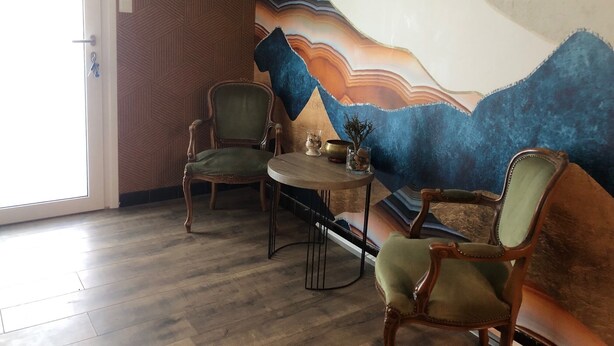 A room with two wooden chairs, a round table, and a large abstract mural on the wall. - Room in house in Bourg-en-Bresse (near Brou church and Ainterexpo) (Bourg-en-Bresse)