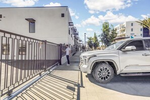 Un área de estacionamiento amparada con una camioneta SUV blanca estacionada a la derecha.