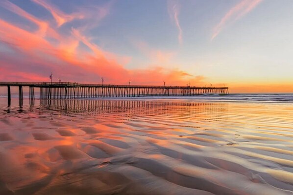 Un muelle se adentra en aguas tranquilas con un atardecer de fondo.