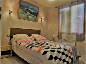 A bedroom with a bed, nightstands, a painting, and a window with curtains. - Gite les Acacias lesgitesdeshautsdevialot.fr (Auriac-du-Périgord)
