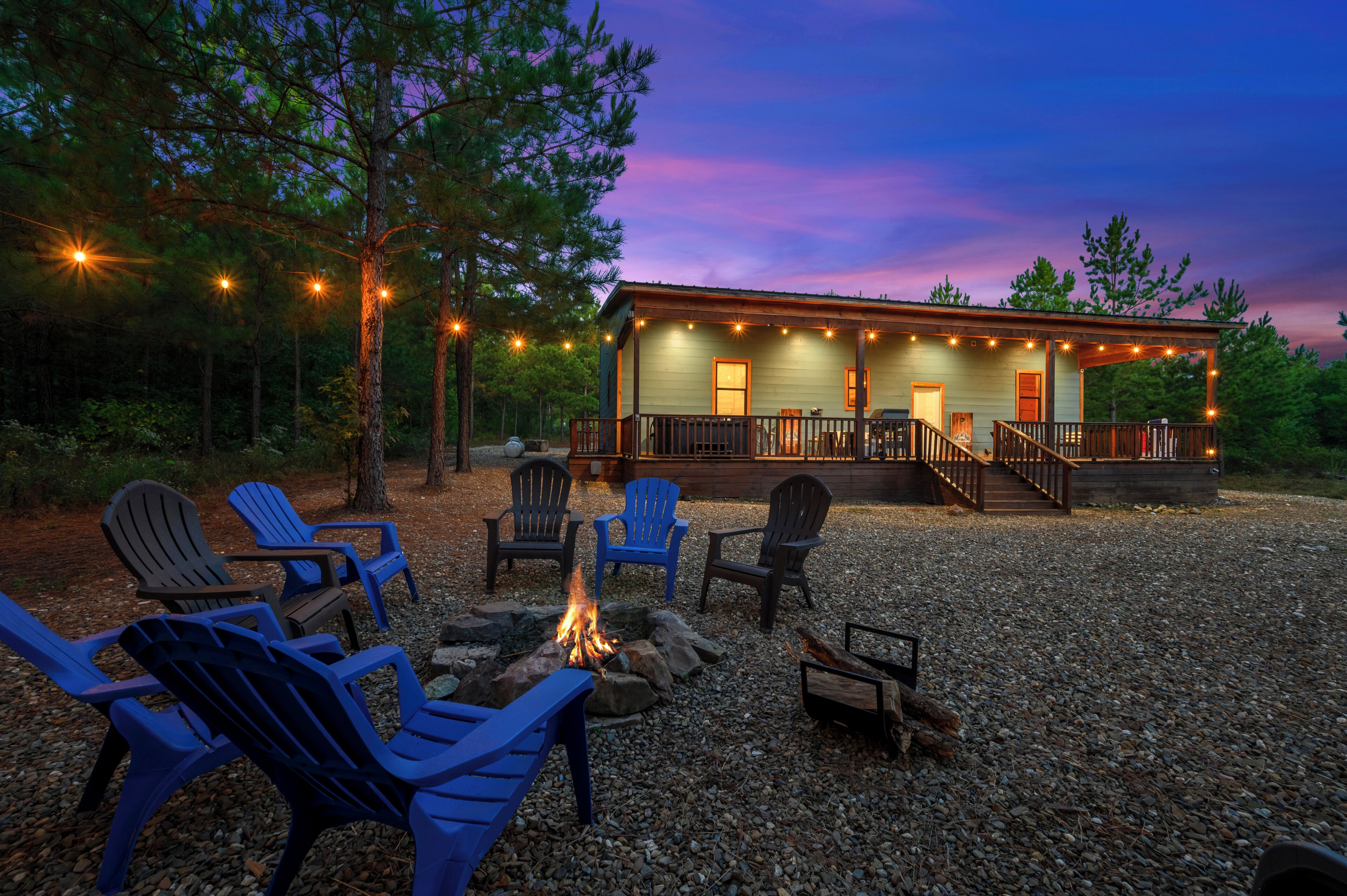 A cabin with a deck, outdoor seating, and a fire pit.