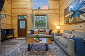 Ein gemütliches Blockhaus-Interieur mit einer Couch, einem Couchtisch und einem großen Fenster.