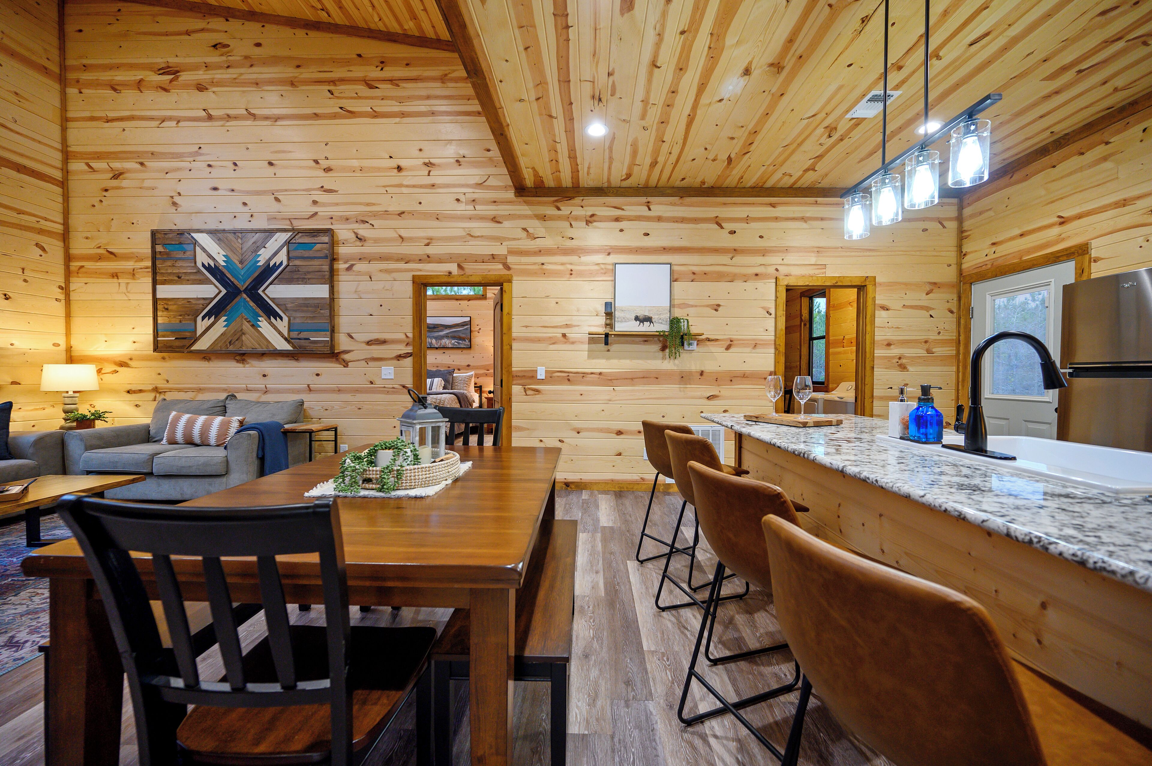 A wooden cabin interior with a dining area, kitchen, and living space.