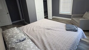Ein Schlafzimmer mit Bett, Schrank, Fenster mit Jalousien und einer Tür.