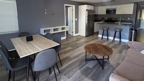 Eine moderne Küche mit Kühlschrank, Mikrowelle und Herd. Es gibt einen Essbereich mit Tisch und Stühlen.