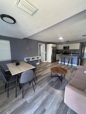 A modern kitchen with a refrigerator, microwave, and stove. There is a dining area with a table and chairs. - Spacious 4-bedroom house in pleasant Tampa, near beaches and downtown (Tampa)