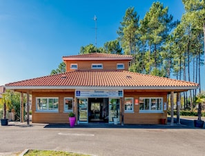 A two-story building with a tiled roof, a signboard, and a small antenna. - Forest Stay for 4 by the Lake (Parentis-en-Born)