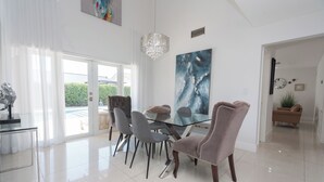 Zona pranzo moderna con tavolo in vetro, sedie grigie e un lampadario.