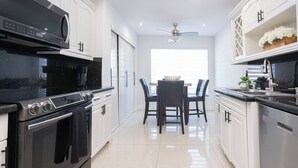 Una cucina moderna con zona pranzo, elettrodomestici in acciaio inossidabile e mobili bianchi.
