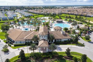 A residential area with a large swimming pool, multiple houses, and a central building with a circular tower. - Luxury 4BR at ChampionsGate w/ Private Pool & BBQ (Davenport)