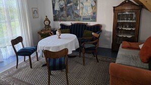 Un coin repas avec une table ronde, des chaises, un tableau, une horloge et un escalier.