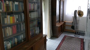 Une pièce avec une bibliothèque en bois, un miroir, un tapis à motifs et un porte-manteau.