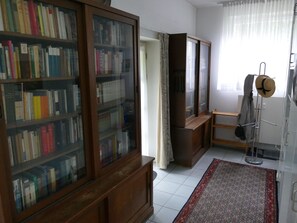 Una habitación con una estantería de madera, un espejo, un tapete estampado y un perchero.