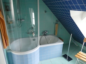 A bathroom with a glass-enclosed shower, a freestanding bathtub, and a corner sink.