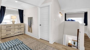 A spacious room with a large window, a wooden dresser, a patterned rug, and a door leading to another room. - Walk to Memphis Nightlife | 100 Yr Old Cozy Apt (Memphis)