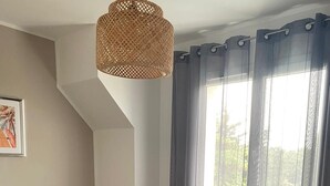 Un dormitorio con una cama, una mesita de noche, una lámpara y una ventana con cortinas.