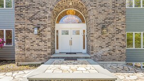 A brick building with a white double door, stone steps, and a decorative archway.