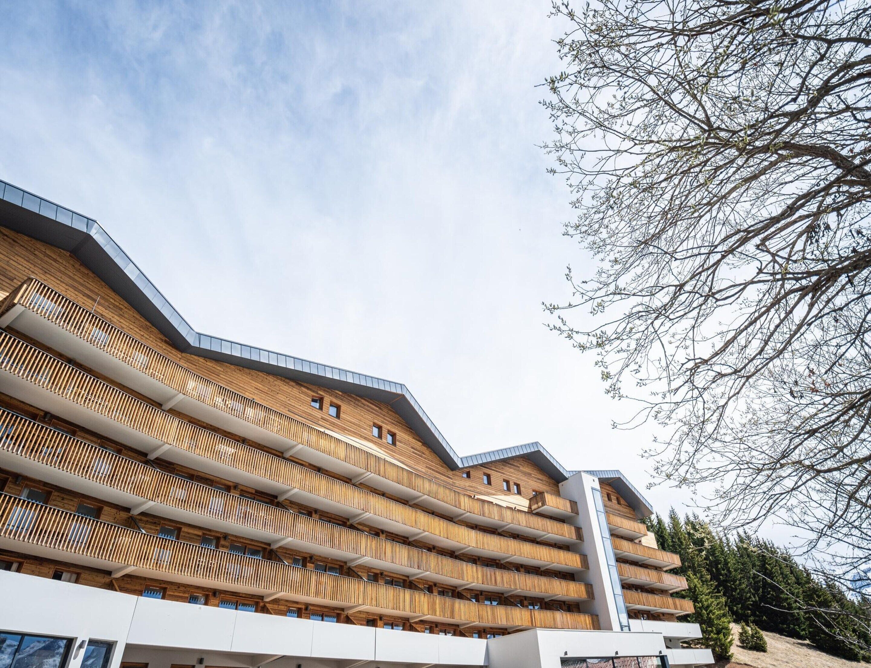 A multi-story building with a modern architectural design, featuring balconies and a prominent vertical structure.