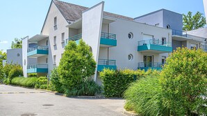 A modern multi-story building with balconies, a parking area, and surrounding greenery. - Studio With Balcony Near Vannes (Plescop)