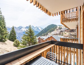 A balcony with a view of snow-capped mountains, wooden railings, and a table with chairs. - Adapted Stay With Ski-in/ski-out Access (Auris)