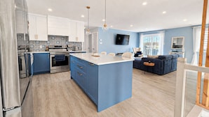 A modern kitchen with blue cabinets, a central island, and stainless steel appliances.