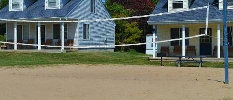 A beach house with a porch, a small attached structure, and a volleyball net.