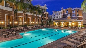 A swimming pool with lounge chairs, palm trees, and a building with multiple stories and balconies. - Elegant Verdant 2BR Retreat with Gym (San Jose)