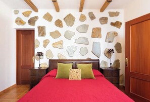 Ein Schlafzimmer mit einem Bett, einem Holzkopfstück, einer Steinwand und einer Holztür.