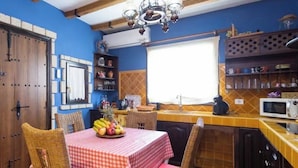 A kitchen with a checkered tablecloth, wicker chairs, a fruit bowl, and a window. - House with a Private Pool and Wi-Fi (El Rio)