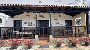 A building with a tiled roof, stone walls, and a porch with potted plants. - House with a Private Pool and Wi-Fi (El Rio)