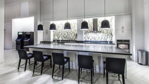 Une cuisine moderne dotée d’un grand îlot central, de luminaires suspendus et de tabourets de bar.