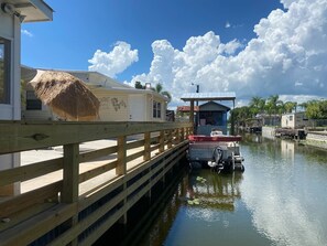 A canal with a wooden dock, a houseboat, and a small boat docked at the pier.