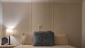 Een hotelkamer met een bed, nachtkastje, lamp en een stopcontact.