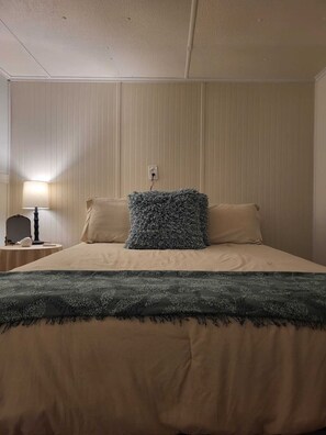 A hotel room with a bed, a nightstand, a lamp, and a wall socket. - Pet Friendly | Private Dock & Direct Canal Access (Okeechobee)