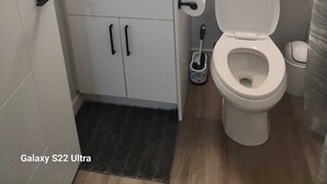 A bathroom with a white sink, a toilet, a mirror, and a towel rack. - Go-HabitAt: Home away from Home (Saskatoon)