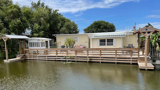A lakeside property with a wooden deck, a covered seating area, and a small pavilion. - Cottage With Dock | 10 Min To  Lake Okeechobee (Okeechobee)