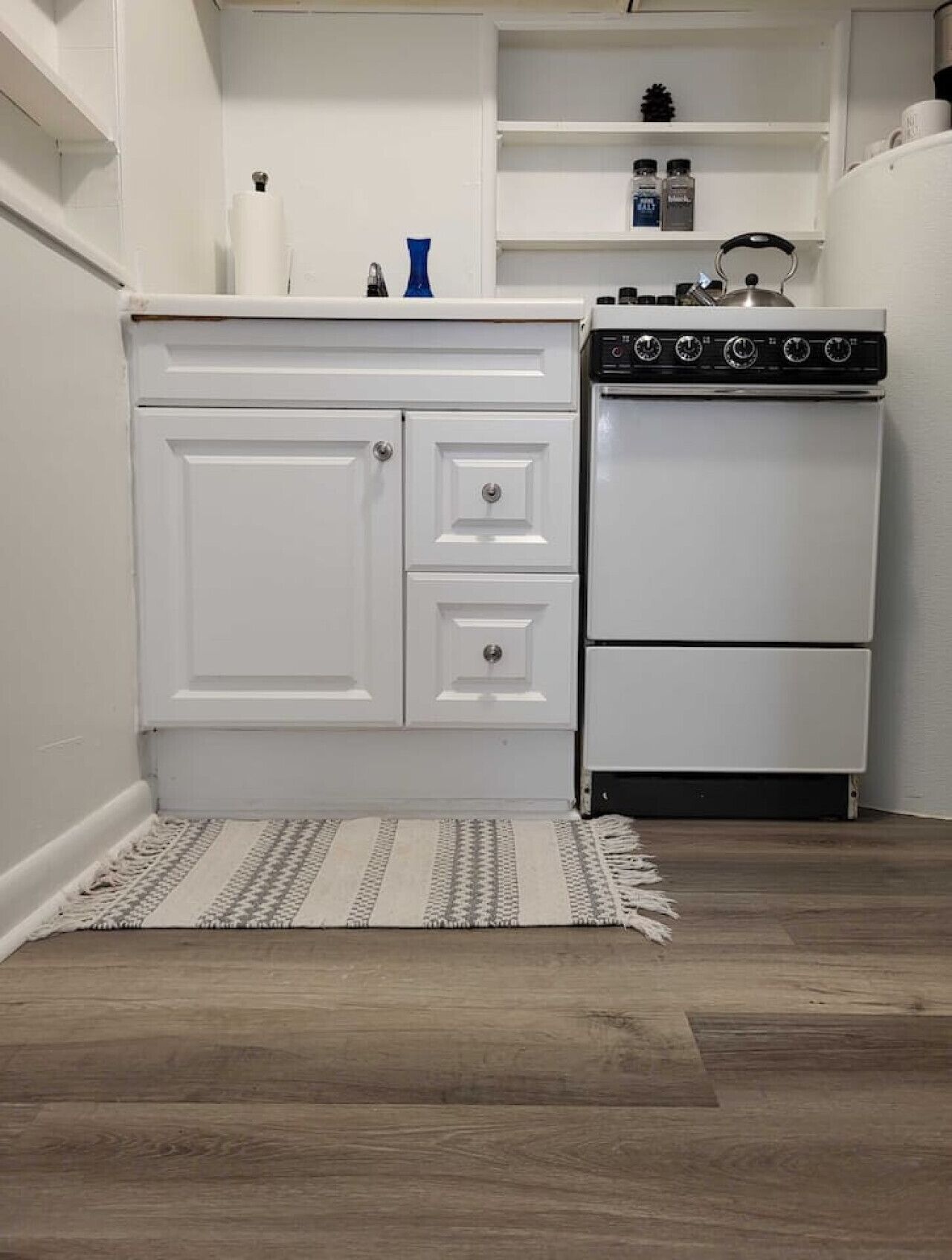 Une cuisine compacte avec des meubles blancs, une cuisinière encastrée et un petit plan de travail.