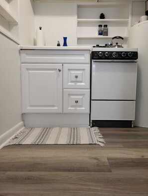 A compact kitchen with white cabinetry, a built-in stove, and a small countertop.