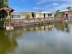 A waterfront property with a wooden dock, a small pavilion, and a building with a blue door. - Private Boat Slip | Fish Off Your Own Private Dock (Okeechobee)